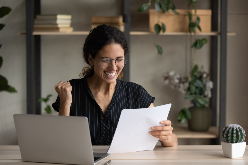 Cheerful young woman celebrating success, reading paper letter.